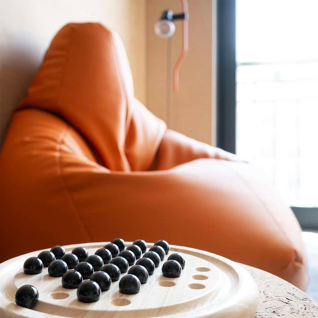 BEING BORN – Office Design für eightbit experts: Detail der Lounge-Area Solitaire-Spiel im Pausenraum der eightbit experts mit Zanotta Sacco Sitzsack und der ikonischen Parentesi-Leuchte, gestaltet von BEING BORN.